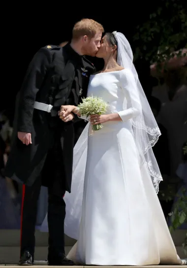Iako se spominjalo kako će je osmisliti Ralph&amp;Russo, Burberry ili Stella McCartney, tamnokosa ljepotica iznenadila je svojom odlukom o vjenčanoj haljini koju je nosila na svadbi sa princom Harryjem. U konačnici je oduševila  minimalističkom haljinom golih ramena koju je dizajnirala pariška modna kuća Givenchy, koju odnedavno vodi Britanka Clare Waight Keller, prva žena u povijesti na čelu te modne kuće. U profinjenoj haljini izrađenoj od najfinije svile s nježnim mat lookom zvijezda &quot;Suitsa&quot; izgledala je prelijepo, a vjenčani stajling upotpunili su tijara i dugački veo s rubom, na kojem su bili izvezeni autohtoni cvjetovi iz 53 zemlje Commonwealtha. 