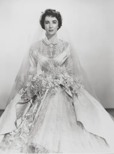 U filmu &quot;The Father of the Bride&quot; iz 1950-e Elizabeth Taylor je zablistala u ovoj senzacionalnoj satenskoj haljini koju je posebno za nju kreirala tada poznata dizajnerica Helen Rose. Haljina je bila bogato ukrašena čipkom, strukirana i napravljena od metara najluksuznijeg satena. 
