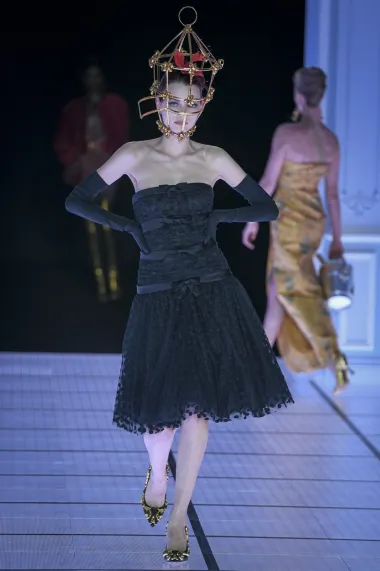 Kavez na glavi - zašto ne? Ovaj je model prošetao u maloj crnoj haljini bez naramenica s točkicama i detaljima mašnica te elegantnim crnim rukavicama, no sve su oči bile uprte u zlatni kavez koji se nalazio na glavi modela. Zlatno-crne salonke savršeno su se uklopile u cijeli outfit.