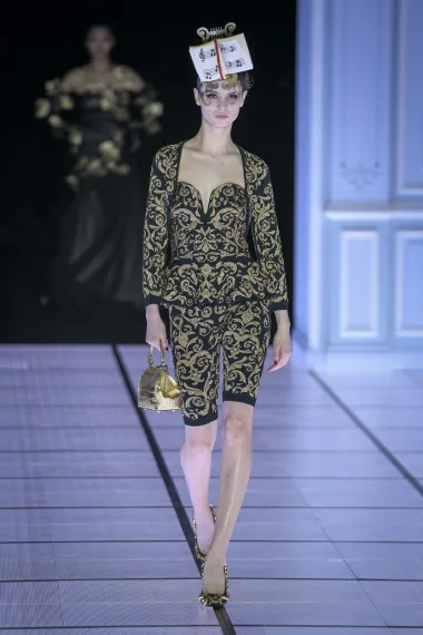 Outfit crno-zlatnog uzorka koji neodoljivo podsjeća na uzorke kakvi su se nosili na kraljevskim dvorima u prošlosti sastoji se od kratkih hlača i elegantne majice, a glavni naglasak je opet na glavi, a ovog je puta riječ o stalku s notama kakvog možemo vidjeti na klaviru.