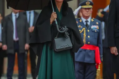 Kraljica Letizia za ovu je prigodu odabrala smaragdnu haljinu na preklop. S obzirom na kišno vrijeme, kraljicu je &apos;grijao&apos;  elegantni crni ogrtačem s krznenim ovratnikom s potpisom modne dizajnerice Caroline Herrere. Iako su za odjevne kombinacije dviju dama mnogi imali riječi hvale, primijetili su da je isti imidž španjolska kraljica već nosila na misi zadušnici pokojnog princa Philippa. Jedina razlika je što ovaj put nije nosila šešir. Uz to, čini se da je kraljici rad Caroline Herrere posebno drag jer je tijekom službenog posjeta Zagrebu nosila i torbicu s istim potpisom. Elegantan stajling zaokružila je kožnim rukavicama u crnoj boji.