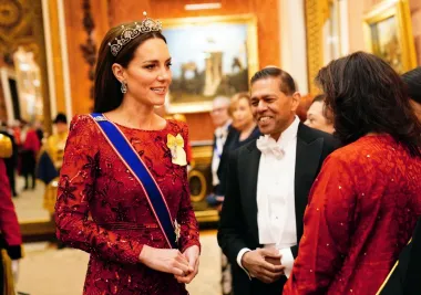 U društvu supruga, princa Williama, kralja Charlesa III. i kraljice Camille, Kate je zablistala u bordo crvenoj haljini svoje omiljene modne dizajnerice Jenny Packham. Radi se u dugoj pripijenoj haljini koja je savršeno istakla princezinu figuru, a haljina je posebno upečatljiva bojom, ali i cvjetnim uzorkom i našivenim šljokicama. Kombinaciju je začinila dijamantnim naučnicama i tijarom &apos;Lotus Flower&apos; koju je još prije četrdesetak godina rado nosila princeza Margaret, pokojna sestra kraljice Elizabete II.