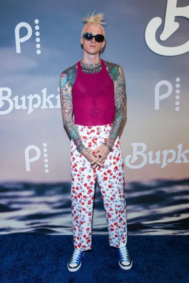 Reper Machine Gun Kelly poznat je po svojim ludim i neobičnim outfitima na crvenim tepisima, a jedan takav bio je i ovaj koji je odabrao za njujoršku premijeru serije &apos;Bupkis&apos;. Nosio je hlače s cvjetnim uzorkom i prozirnu ružičastu majicu ispod koje su se nazirale njegove tetovaže, a sve je začinio ludim detaljima, poput naočala, ali i frizure.
