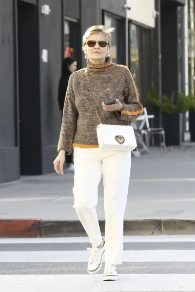 Sharon Stone uvijek nas oduševljava sa svojim svečanim izdanjima, ali ni casual outfiti nisu iznimka jer svaki put izgleda vrlo šik. Za šetnju gradom odjenula je smeđi pulover s visokim ovratnikom, bijele ravne hlače i bijele tenisice te Dolce&amp;Gabbana torbicu.