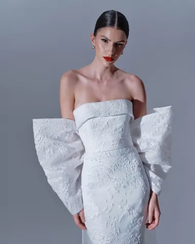 Posve novi modeli uvode smjele detalje poput voluminoznih mašni, prozirnih materijala, dubokih proreza i elegantno ogoljenih leđa, dok teksture poput svilenog satena, eko perja i tkanina prekrivenih kristalima pružaju dozu luksuza koja oduzima dah.