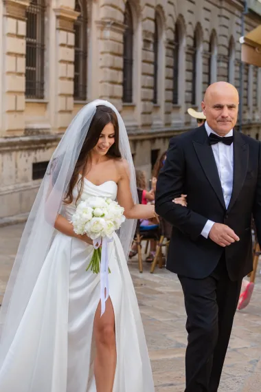 Helena Livaković za svoj je veliki dan odabrala svilenu vjenčanicu dizajnera Narcisa Rodrigueza čiji je gornji dio krasio asimetrični korzet s profinjenim naborima i delikatnom tankom naramenicom. Donji dio haljine isticao se elegantnim preklopom, visokim prorezom i raskošnim šlepom, što je cijelom izgledu dalo dozu sofisticirane drame.
