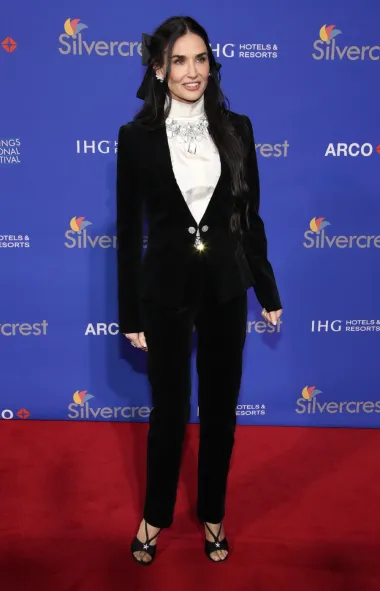 U elegantnom crnom Chanel odijelu od baršuna, koje se sastoji od uskog sakoa s prekrasnim, velikim metalnim dugmadi i uskih hlača. Ovaj sofisticirani look upotpunjen je bijelom bluzom s dekorativnim kristalnim detaljima na vratu. 