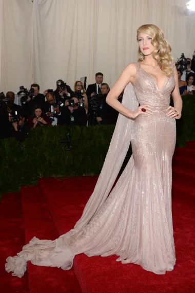 Blake Lively na Met Galu je povela supruga Ryana Reynoldsa, što je označilo njihovo prvo pojavljivanje na crvenom tepihu kao par. Tada je  zablistala u pripijenoj ružičastoj haljini s dugim šlepom iz kolekcije Gucci Première, koja je prizivala glamur zlatnog doba Hollywooda.