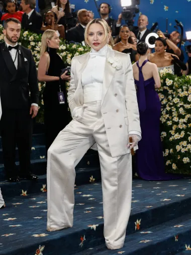 Držeći se dress codea večeri, glazbena ikona Madonna predstavila je svoju interpretaciju u dvorednom sakou, bijeloj košulji i leptir-mašni. Njezin androgini look dodatno je naglašen odvažnim ružem u fuksija nijansi i zadimljenim tušem za oči, dok je cijelom izgledu dodala dozu drame – pušeći cigaru na crvenom tepihu. Ovaj upečatljiv styling potpisuje Haider Ackermann za Tom Ford.